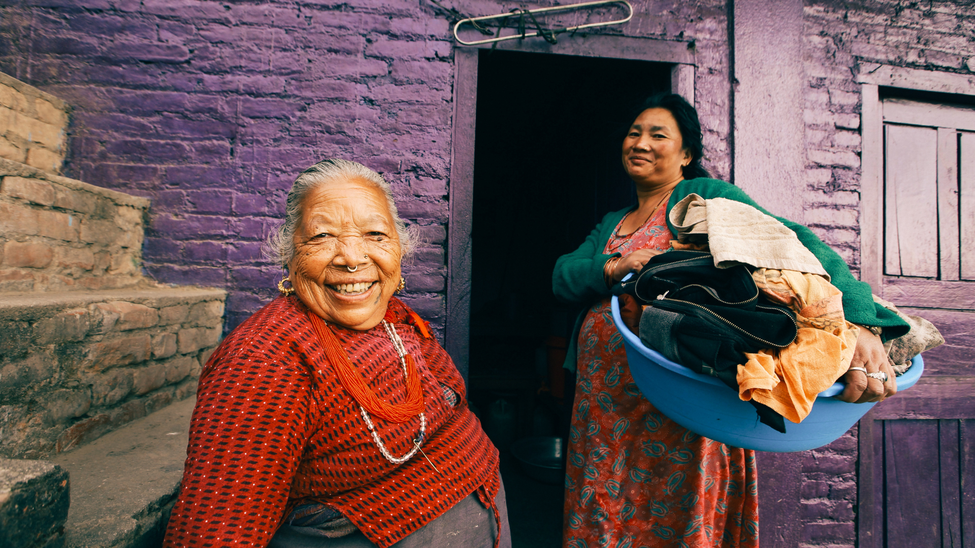 Dos mujeres de ascendencia asiática en un entorno de vivienda empobrecida.
